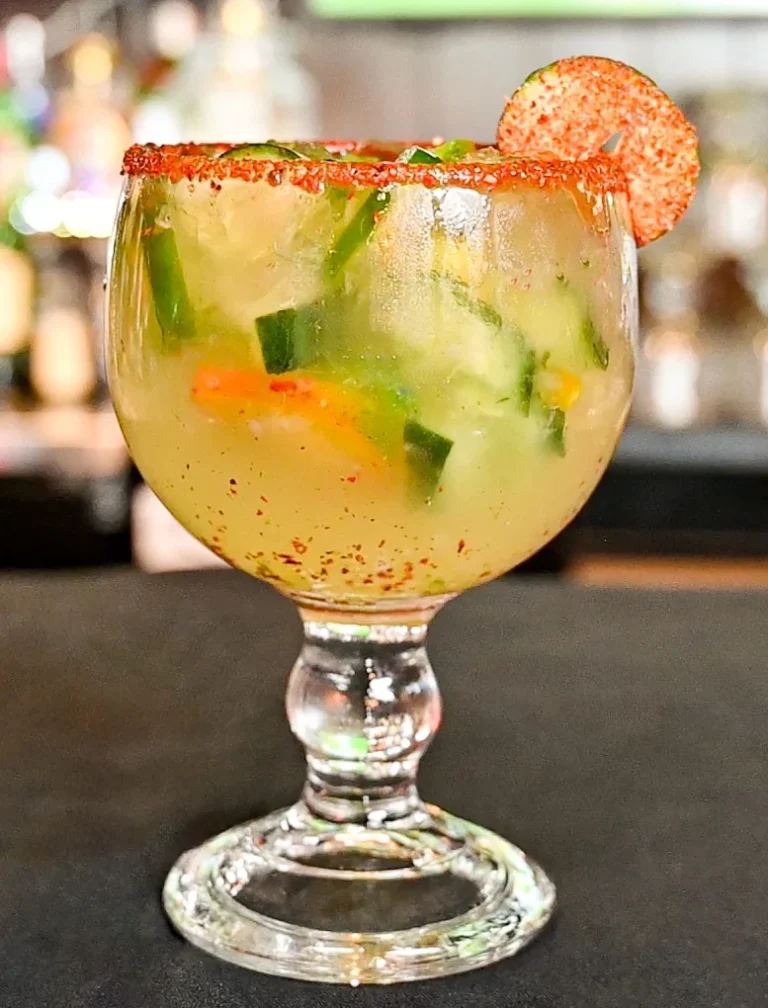 Cucumber jalapeño margarita with cucumber slices and a tajín rim